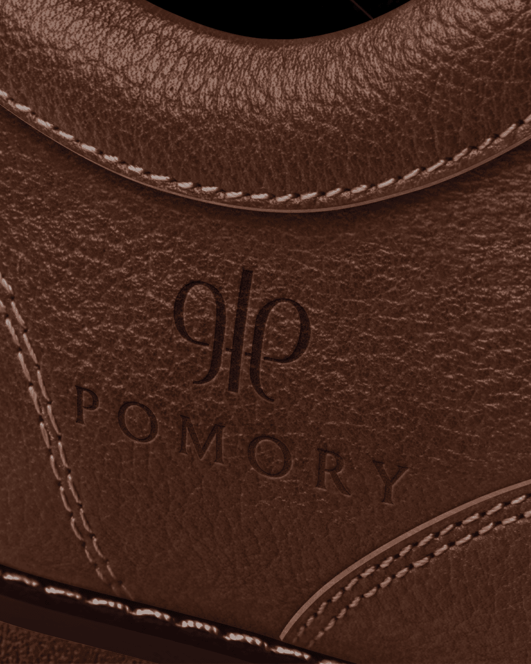 Close-up of the Pomory logo embossed into full-grain leather